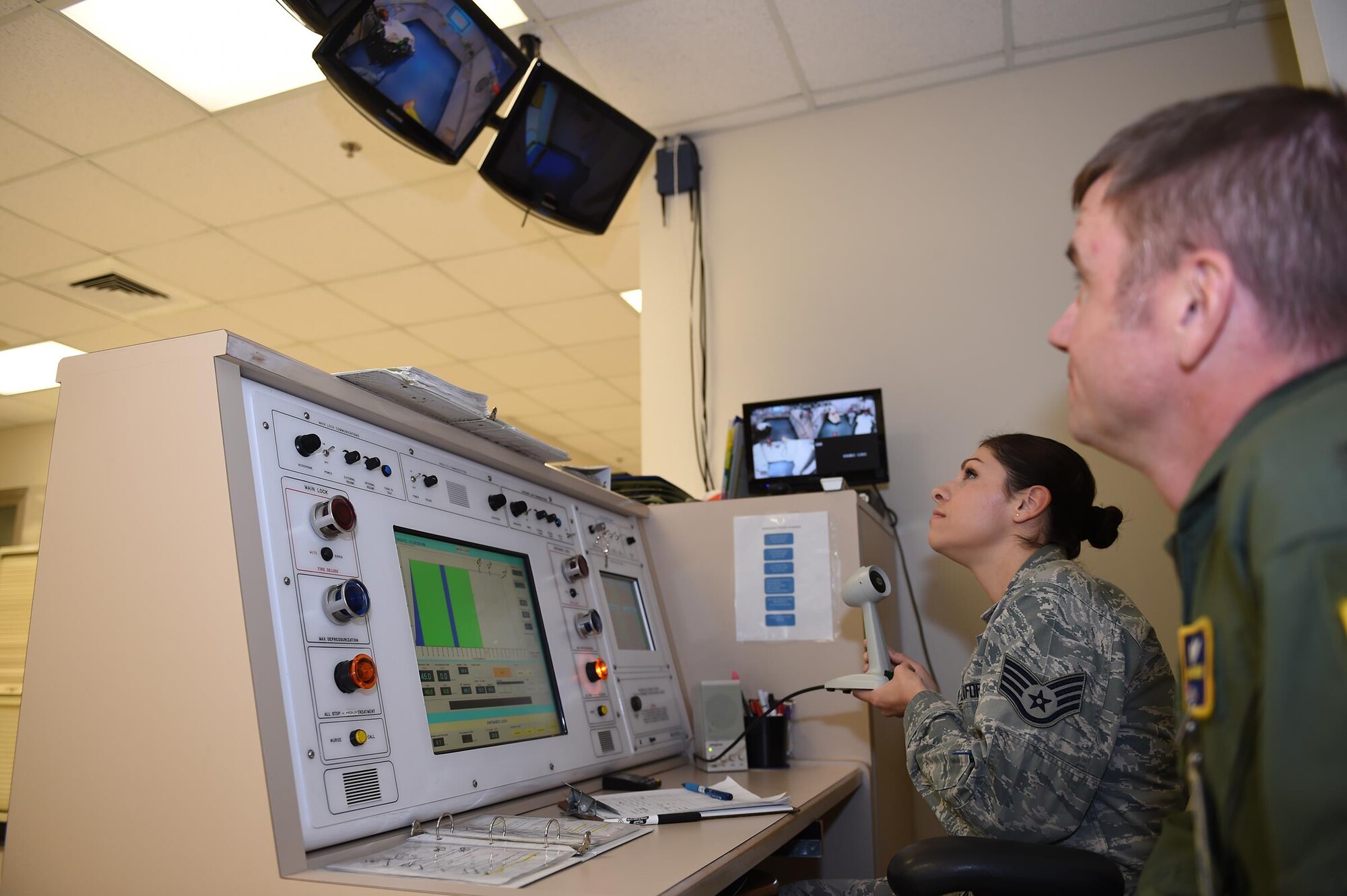 Col. Michael Richards and Staff Sgt. Maribel Cortez communicate with patients undergoing treatment in the multiplace hyperbaric chamber at the Wilford Hall Ambulatory Surgical Center, Joint Base San Antonio-Lackland, Nov. 18, 2015. Patients are closely monitored during each dive by technicians and doctors, both inside and out of the chamber, to ensure patient safety at all times. Richards is the 59th Hyperbaric Medicine Flight commander; Cortez is a hyperbaric medical technician. (U.S. Air Force photo / Tech. Sgt. Christopher Carwile)
