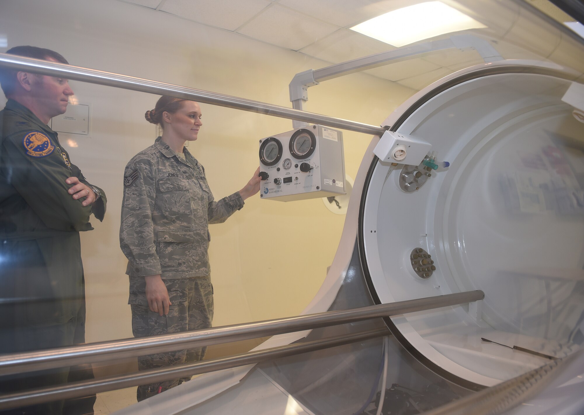 Col. Michael Richards, 59th Hyperbaric Medicine Flight commander, observes as Staff Sgt. Sherri Jones, hyperbaric medical technician, demonstrates the controls of the monoplace hyperbaric chamber at the Wilford Hall Ambulatory Surgical Center, Joint Base San Antonio-Lackland, Nov. 18, 2015. Treatments in the chamber help wounded warriors, diabetics and cancer patients recover more quickly from their ailments. (U.S. Air Force photo / Tech. Sgt. Christopher Carwile)
