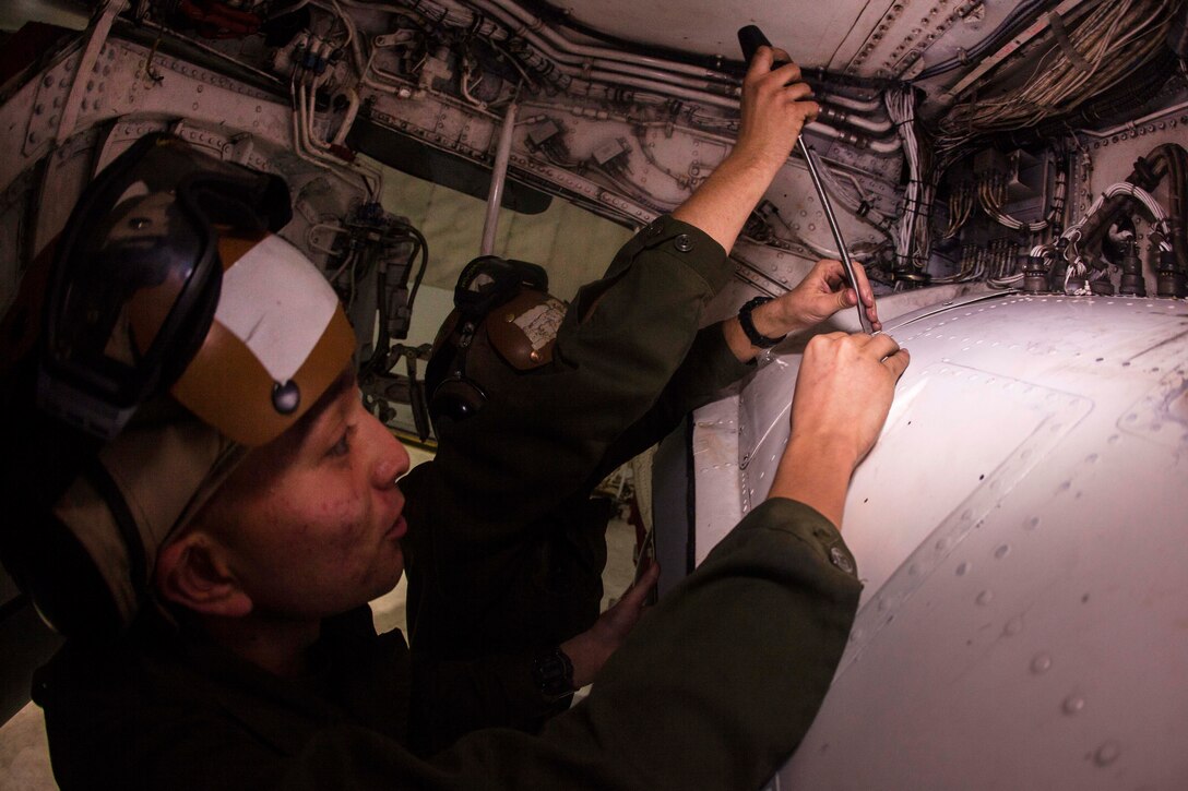 Marine Corps Lance Cpls. Adam J. Duran, left, and Travis R. Williams tighten rivets on an EA-6B Prowler engine on Marine Corps Air Station Cherry Point, N.C., Dec. 1, 2015. Duran and Williams are power plant mechanics assigned to Marine Tactical Electronic Warfare Squadron 2. U.S. Marine Corps photo by Lance Cpl. Jered T. Stone