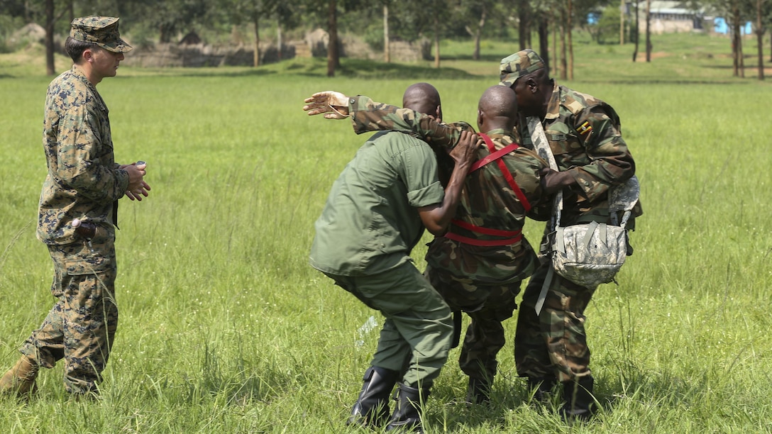 Petty Officer 2nd Class Robert Otte (left), corpsman and chief instructor with Special-Purpose Marine Air-Ground Task Force Crisis Response-Africa, evaluates Uganda People’s Defense Force medics as they carry and injured soldier to a safe zone during a tactical combat casualty care exercise at Camp Singo, Uganda, Dec. 8, 2015. The UPDF medics and corpsmen are training together to improve tactical medical care skills while strengthening the bond between the partner nations. 