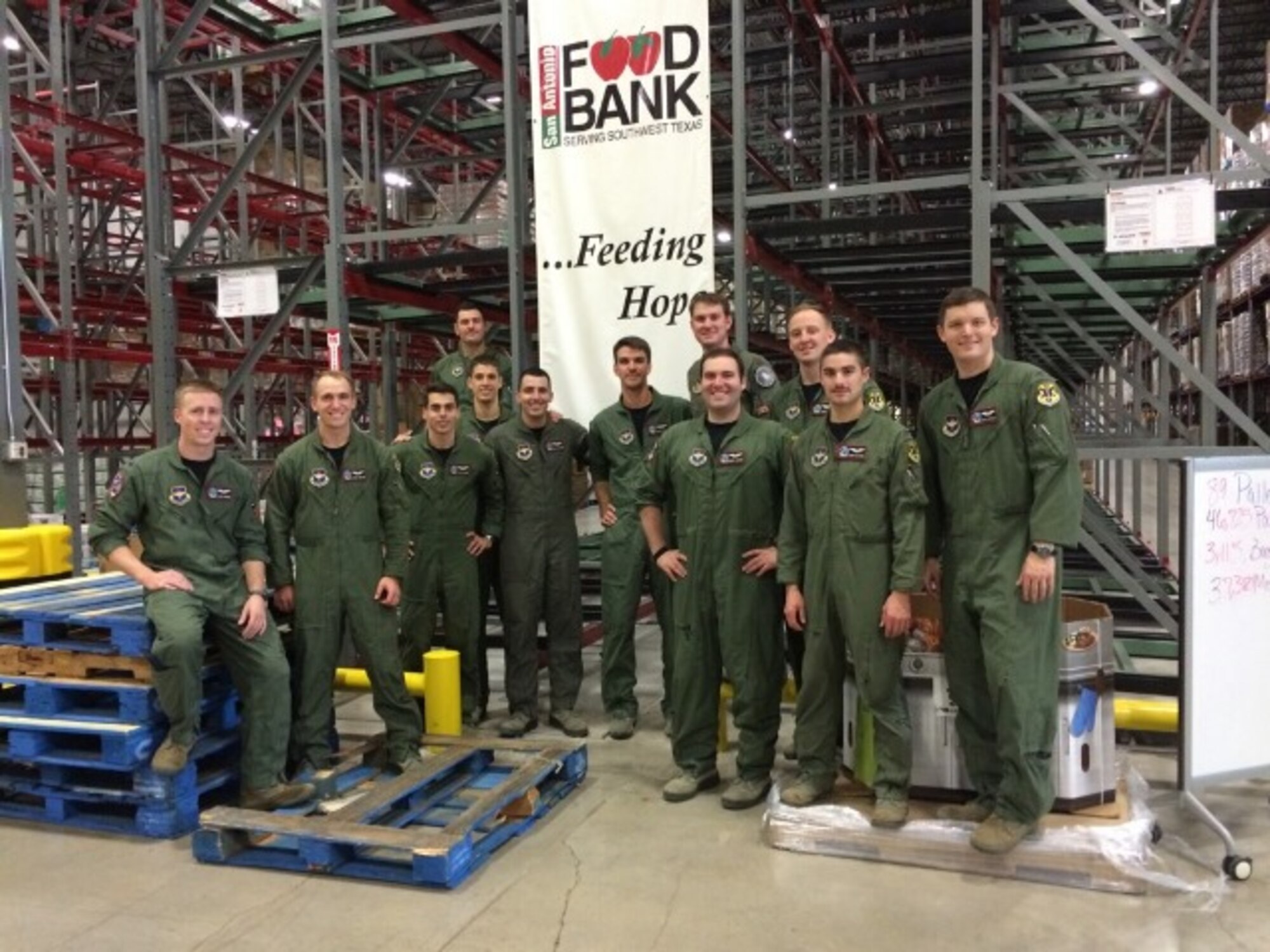 Members of 435th Flying Training Squadron class 16-DBR from Joint Base San Antonio-Randolph take a break after packing 49,875 pounds of food on 95 pallets for distribution to the local community in the form of 39,900 meals to 3,325 local families while at the San Antonio Food Bank Dec. 12, 2015.  The community outreach project, part of the unit’s Wingman Day, broke the single-day record for food packed at the food bank. (U.S. Air Force courtesy photo)