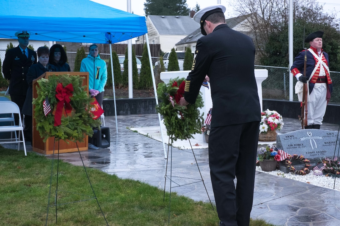 Navy Command Master Chief David Lynch, foreground, from Naval Base Kitsap, places a Navy flag in a wreath during the Wreaths Across America wreath-laying ceremony at Ivy Green Cemetery in Bremerton, Wash., Dec. 12, 2015. U.S. Navy photo by Petty Officer 3rd Class Seth Coulter