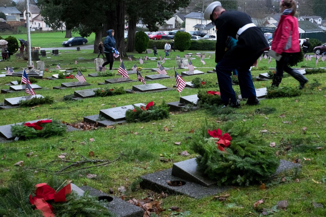 A Marine and volunteer lay wreaths on graves of veterans during the Wreaths Across America wreath-laying ceremony at Ivy Green Cemetery in Bremerton, Wash., Dec. 12, 2015. U.S. Navy photo by Petty Officer 3rd Class Seth Coulter