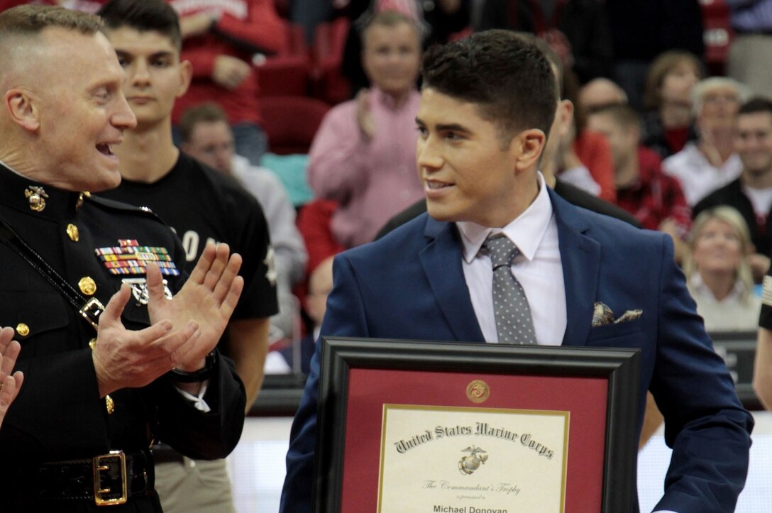 Michael Donovan (center-left), an electrical engineering and mathematics
major originally from Appleton, Wis., receives the Marine Corps Commandant's
Trophy from Col. Jason Morris, 9th Marine Corps District commanding officer,
during a basketball game at University of Wisconsin-Madison, Dec. 9.
