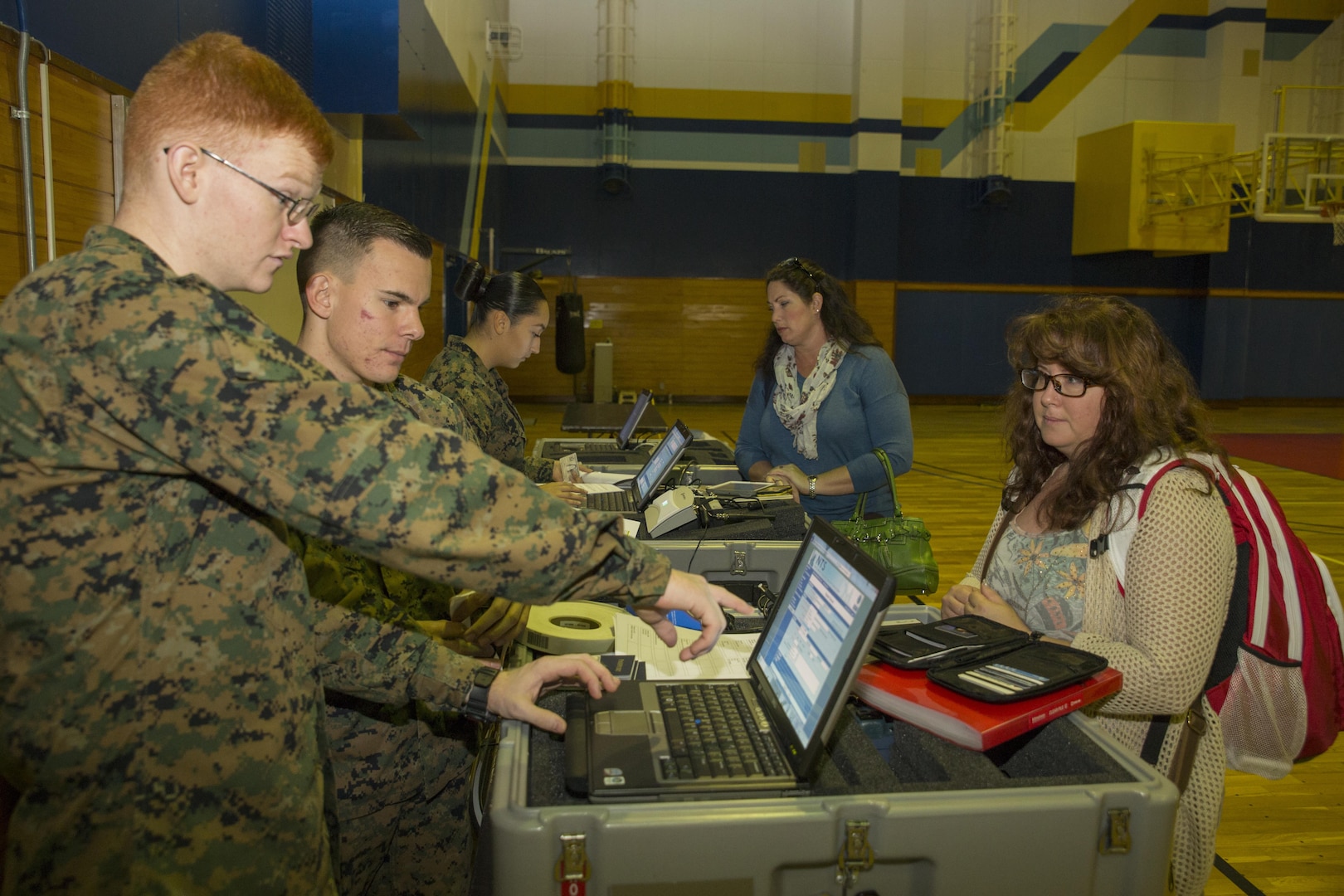 From left to right, Lance Cpl. David Walker, Pfc. Damian Cooper and Pfc. Julie Cary, administrative specialists with the Installation Personnel Administration Center, gather information from residents during a noncombatant evacuation processing center exercise in the IronWorks Gym at Marine Corps Air Station Iwakuni, Japan, Dec. 11, 2015. This exercise practices evacuating endangered personnel in a host-foreign nation to a safe location. Evacuees include noncombatants, nonessential military personnel, select host-nation citizens and third country nationals.