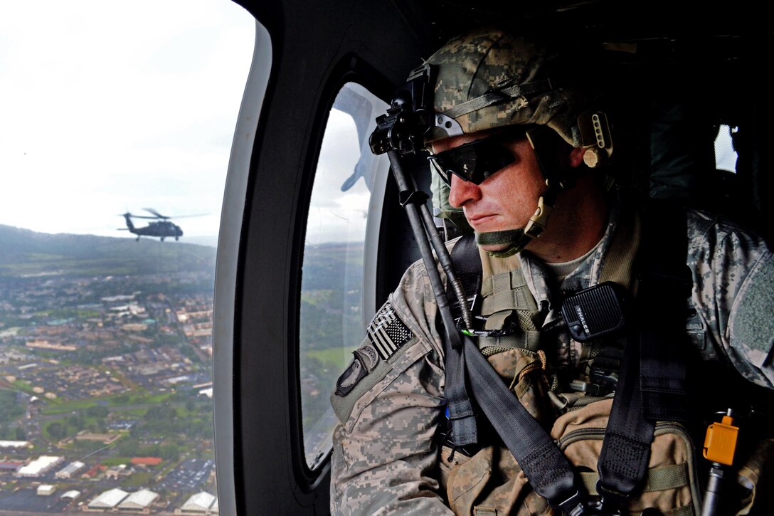 Army Sgt. 1st Class William Henderson looks down at Wheeler Army Airfield, Hawaii, Dec. 2, 2015, as he flies aboard a UH-60 Black Hawk helicopter. Henderson is a platoon sergeant assigned to the 25th Infantry Division's Company B, 2nd Battalion, 35th Infantry Regiment, 3rd Brigade Combat Team. U.S. Army photo by Staff Sgt. Armando Limon