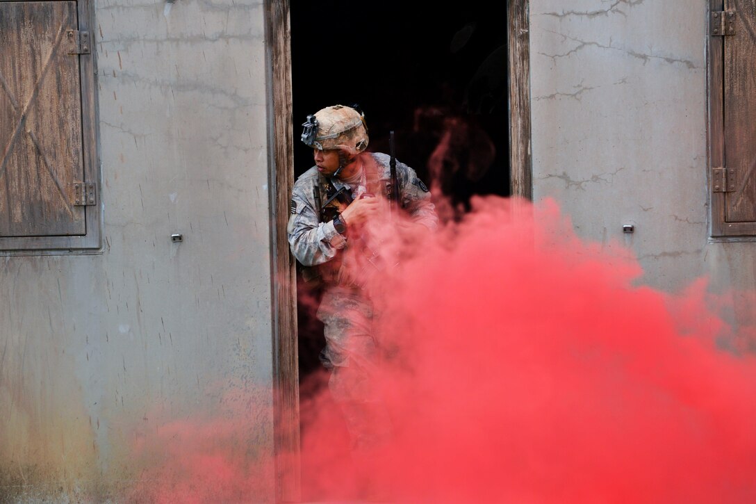 A soldier looks outside a doorway during a training exercise on Marine Corps Training Area Bellows, Hawaii, Dec. 2, 2015. U.S. Army photo by Staff Sgt. Armando Limon