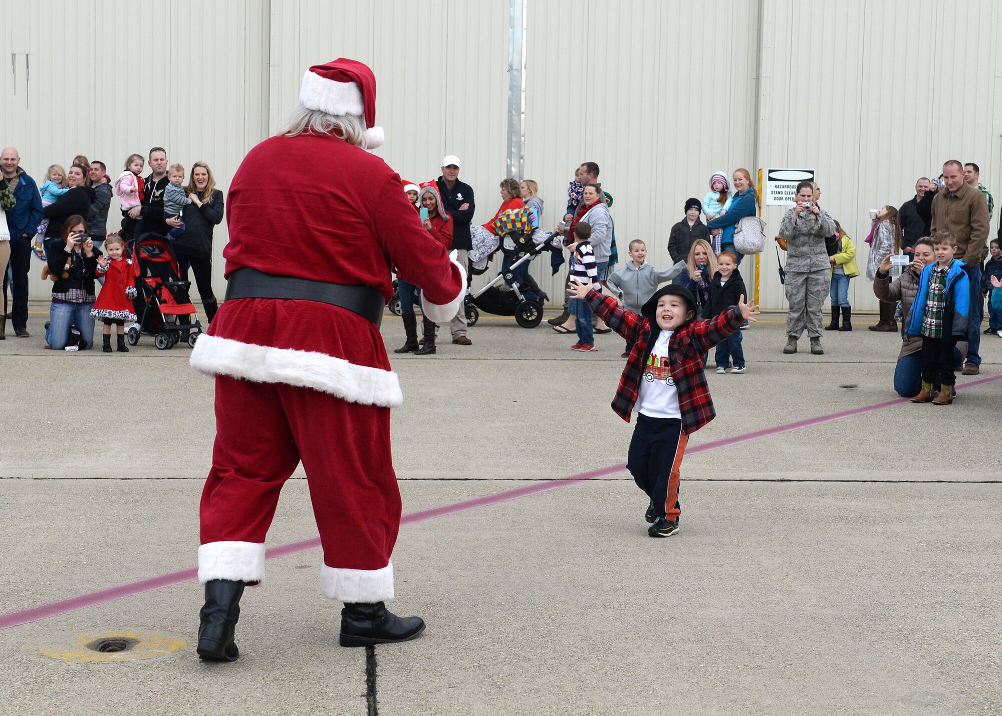 A child of Team Beale runs to Santa Clause during the annual Children's Holiday Party Dec. 12, 2015, at Beale Air Force Base, California. Thousands of presents were donated by multiple suppliers and were handed out to the children of Team Beale. In addition, the event included photos with Santa Clause and his elves, a raffle and various holiday activities. (U.S. Air Force photo by Airman 1st Class Ramon A. Adelan)