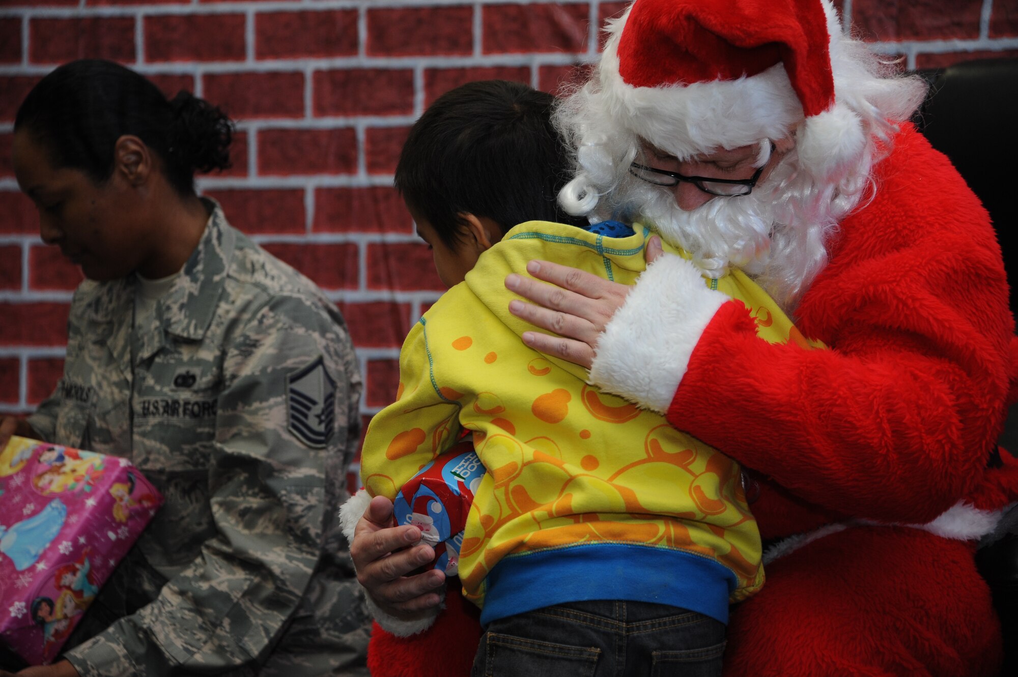 Santa Claus hugs a San Xavier Mission School student during Davis-Monthan Air Force Base’s 50th Anniversary Santas in Blue event in Tucson, Ariz., Dec. 10, 2015. Santas in Blue collected gifts for approximately 1,200 students for its 50th year anniversary this year.  (U.S. Air Force photo by Airman 1st Class Ashley N. Steffen/Released)
