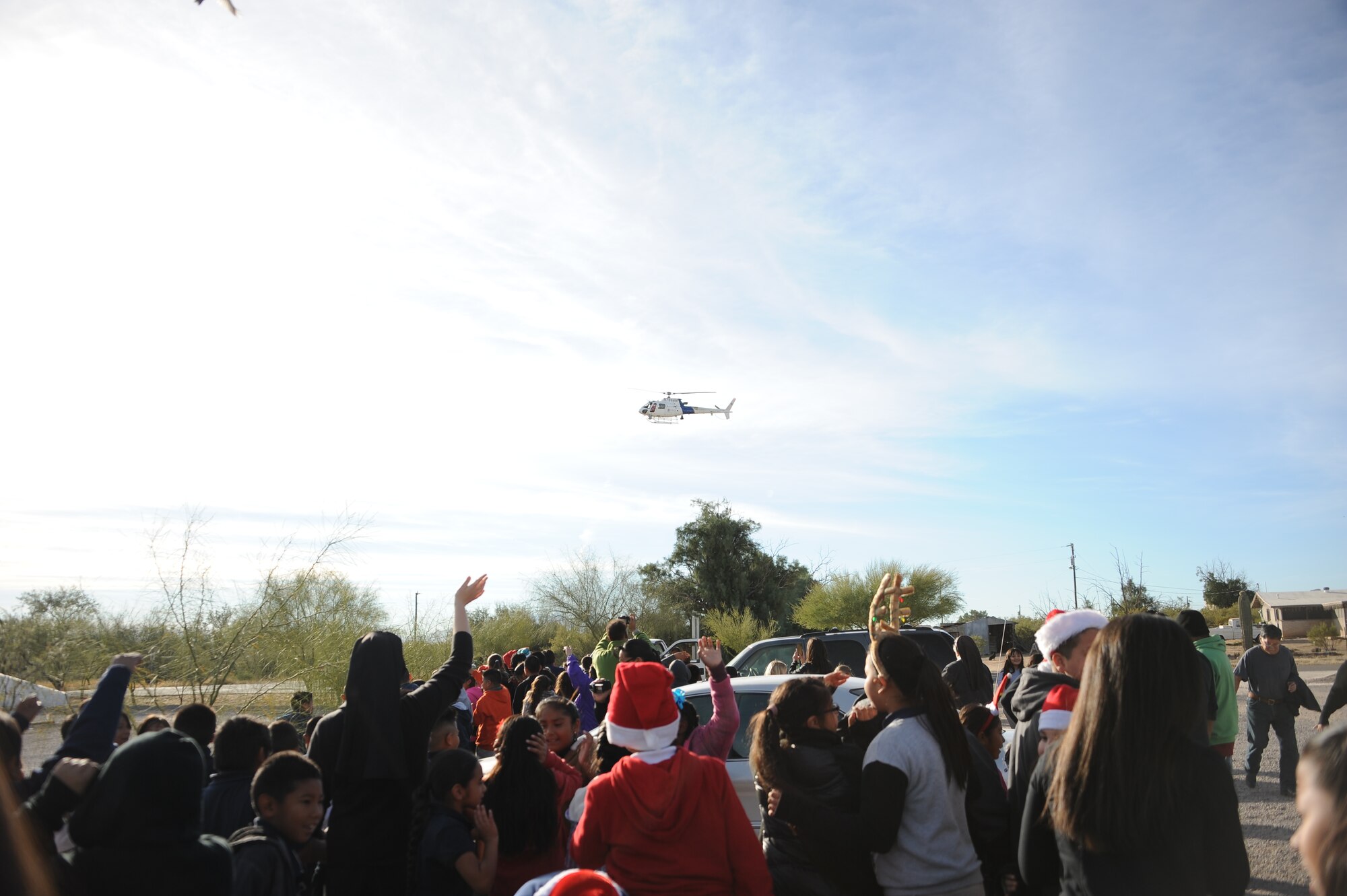 Students wait for a U.S. Customs and Border Protection’s Office of Air and Marine AS-350 Light Enforcement Helicopter to deliver Santa Claus during Davis-Monthan Air Force Base’s 50th Anniversary Santas in Blue event at San Xavier Mission School in Tucson, Ariz., Dec. 10, 2015.  Airmen from D-M AFB helped Santa Claus distribute gifts to each student at the school. (U.S. Air Force photo by Airman 1st Class Ashley N. Steffen/Released)