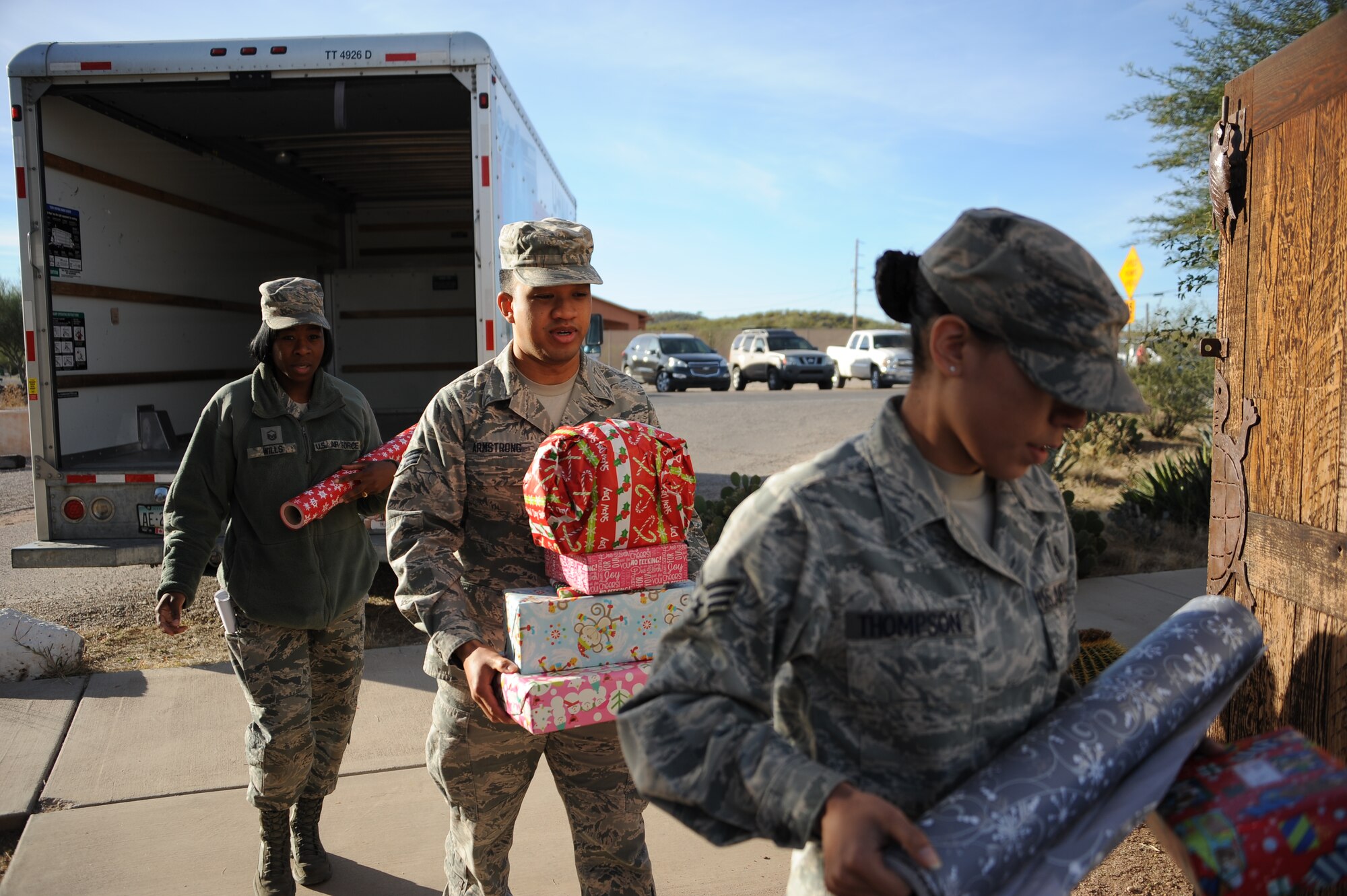 U.S. Airmen from Davis-Monthan Air Force Base, Ariz., carry donated gifts during D-M AFB’s 50th Anniversary Santas in Blue event at San Xavier Mission School in Tucson, Ariz., Dec. 10, 2015.  D-M AFB Airmen donated gifts that were handed out at four different schools and allowed each child to receive a gift. (U.S. Air Force photo by Airman 1st Class Ashley N. Steffen/Released)