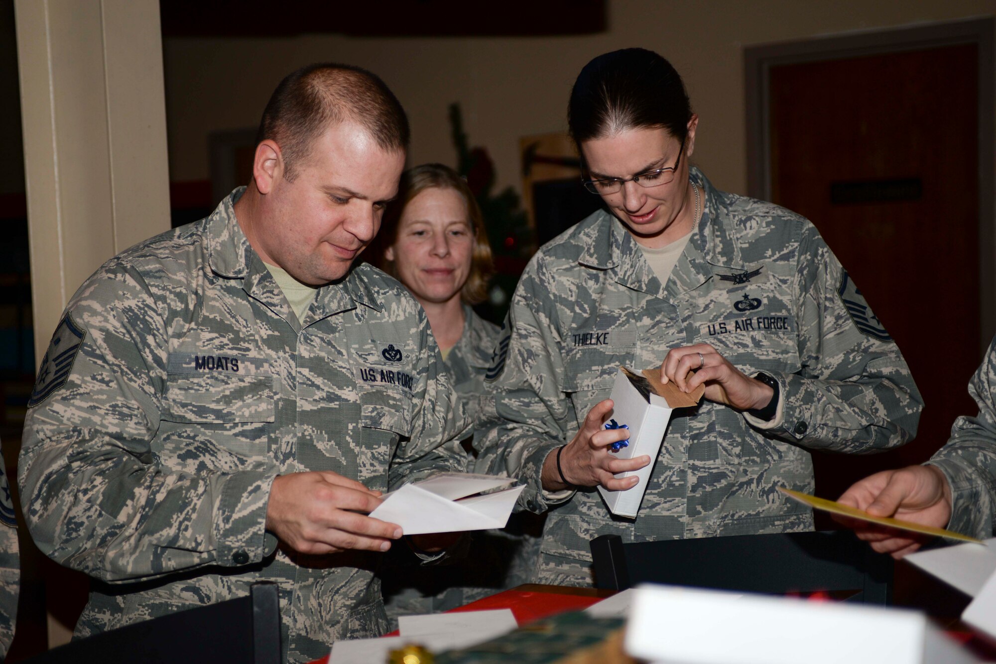 Master Sgts. David Moats, 28th Munitions Squadron first sergeant, left, Tametha McNelley, 28th Communications Squadron first sergeant, center, and Jennifer Thielke, 28th Maintenance Squadron first sergeant, right, look at their organizations’ gifts at Ellsworth Air Force Base, S.D., Dec. 9, 2015. The first sergeants were presented a mug, small tool set and lantern at a surprise party organized to show appreciation for what they do for Ellsworth Airmen. (U.S. Air Force photo by Airman Sadie Colbert/Released)