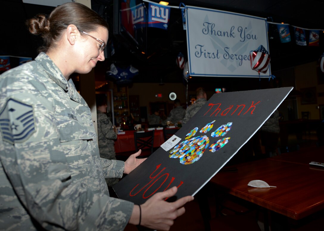 Master Sgt. Jennifer Thielke, 28th Maintenance Squadron first sergeant, looks at a thank you poster from her unit during a first sergeant surprise party at Ellsworth Air Force Base, S.D., Dec. 9, 2015. First sergeants are 24/7 special duty senior NCOs who provide a dedicated focal point for readiness, health, morale, welfare and quality-of-life issues within their organization. (U.S. Air Force photo by Airman Sadie Colbert/Released)