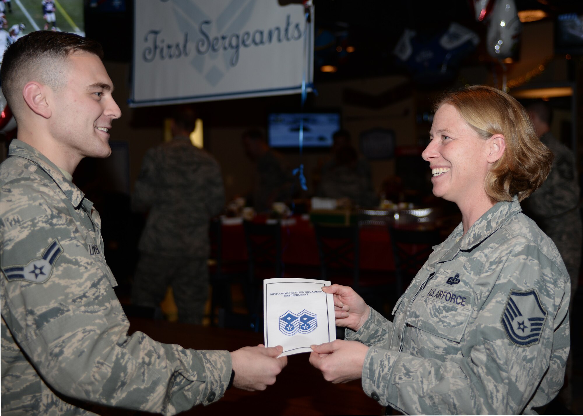 Airman 1st Class Austin Livengood, 28th Communications Squadron knowledge management journeyman, left, hands Master Sgt. Tametha McNelley, 28th CS first sergeant, a thank you card at a first sergeant surprise party at Ellsworth Air Force Base, S.D., Dec. 9, 2015, honoring them for the support they give Airmen. (U.S. Air Force photo by Airman Sadie Colbert/Released)