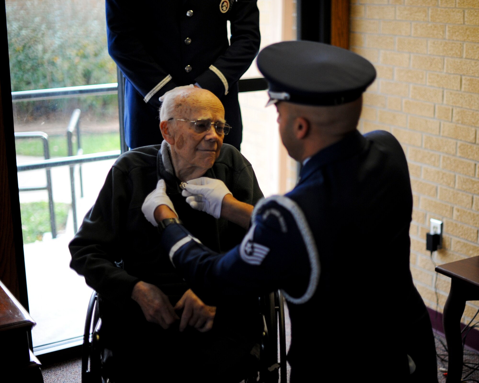 Tech. Sgt. Terrance Williams, 22nd Air Refueling Wing Honor Guard NCO in charge, places a veteran’s pin on the collar of Roy Mullinax, a World War II veteran, Dec. 8, 2015, in Newton, Kan. Mullinax enlisted in the Army towards the end of World War II before joining the Air Force and working for the federal government for more than 50 years before his retirement in 2004. (U.S. Air Force photo/Senior Airman Victor J. Caputo)