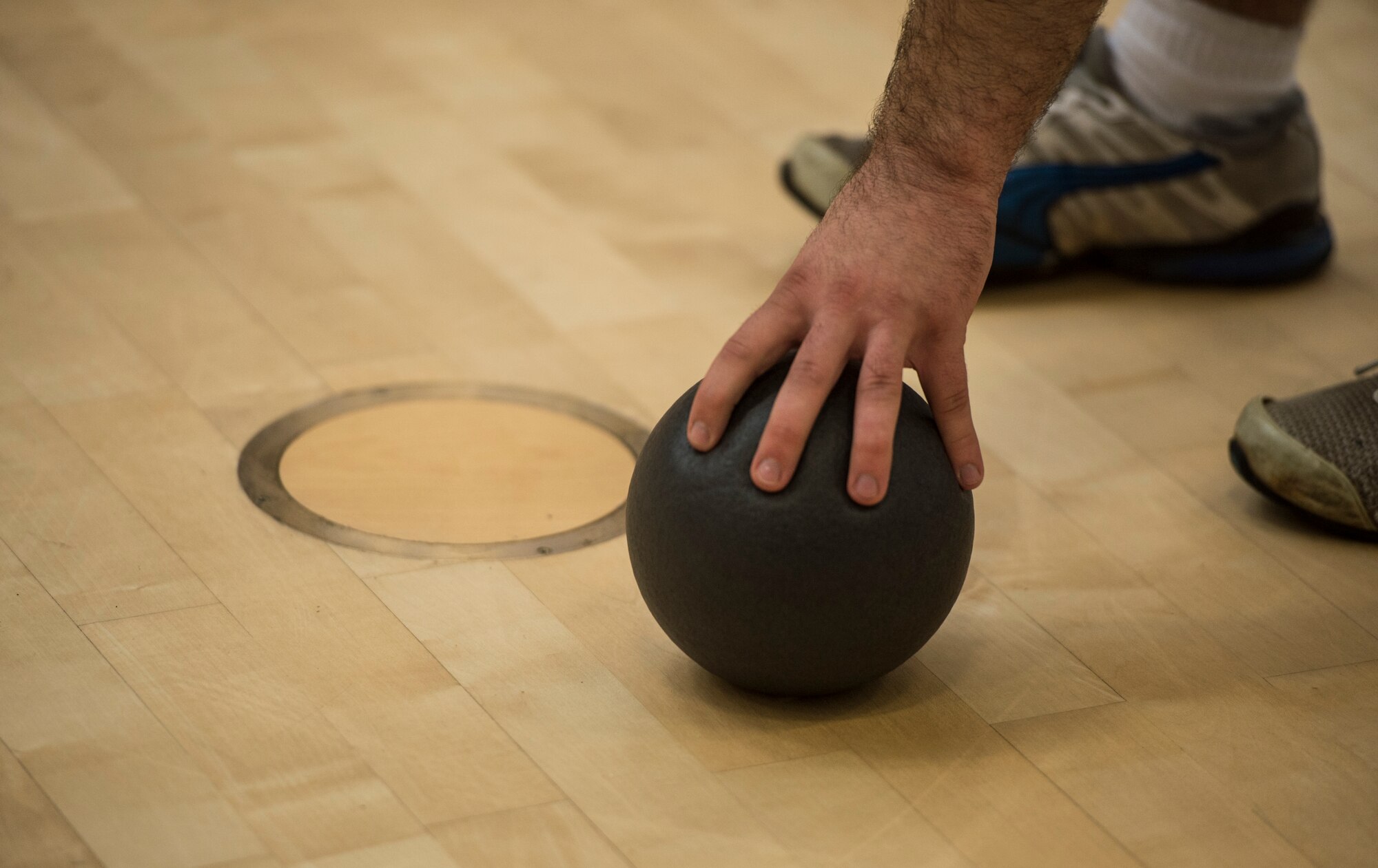 An Airman grabs a dodgeball during the RUFit Dodgeball Tournament in the fitness center Dec. 11, 2015, at Spangdahlem Air Base, Germany. Seven teams participated in the combat fitness-style of dodgeball with the ‘Mighty 606’ taking first place. (U.S. Air Force photo by Staff Sgt. Christopher Ruano/Released)