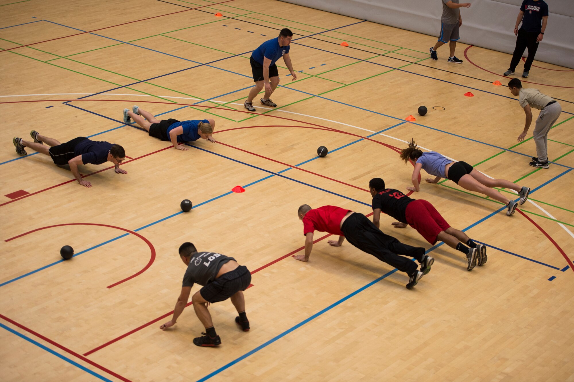 Airmen perform burpees before the start of a dodgeball game during the RUFit Dodgeball Tournament in the fitness center Dec. 11, 2015, at Spangdahlem Air Base, Germany. The combat fit-style dodgeball game had players perform multiple exercise routines if they were struck with the dodgeballs during their game. (U.S. Air Force photo by Staff Sgt. Christopher Ruano/Released)