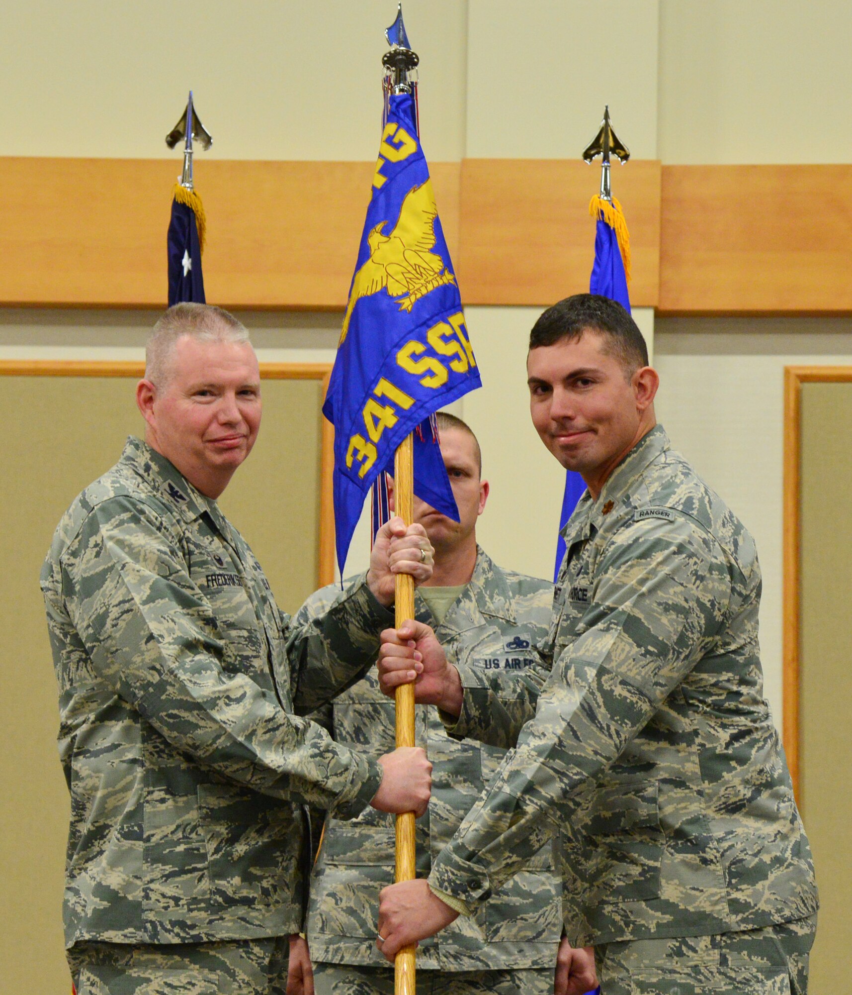 Maj. James Hewett, right, accepts command of the 341st Security Support Squadron from Col. Chris Frederiksen, 341st Security Forces Group commander, during a change of command ceremony at the Malmstrom Air Force Base Grizzly Bend Dec. 11. Master Sgt. Jason Whitehead, 341st SSPTS first sergeant, center, looks on. (U.S. Air Force photo/Airman Daniel Brosam)