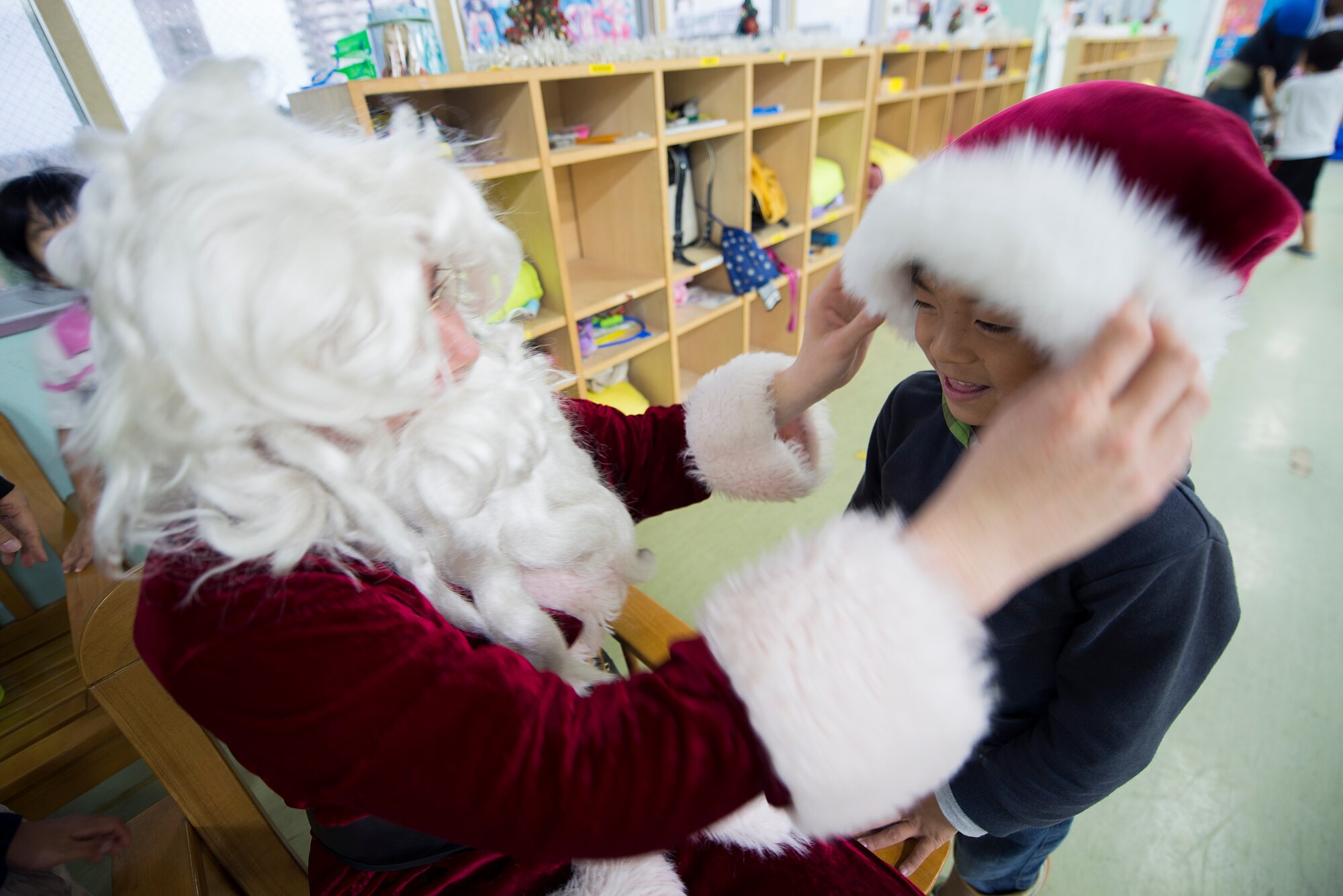 U.S. Air Force Airman 1st Class Darren Dalton, 18th Communications Squadron cable and antenna systems technician, places his Santa Claus costume hat on a child at the Midori School-Age Program during a volunteer visit, Dec. 10, 2015, in Okinawa City, Japan. Fourteen volunteers from Kadena’s Top 3 and the 18th Communications Squadron brought a little Christmas cheer when they visited the SAP. This gave the kids the opportunity to indulge in American Christmas customs by decorating cookies and meeting Santa Claus. (U.S. Air Force photo by Staff Sgt. Maeson L. Elleman)