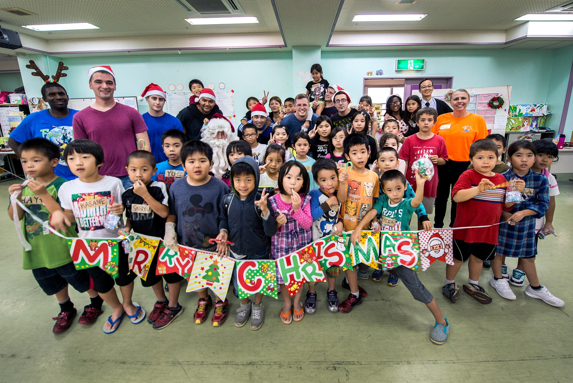 U.S. Air Force volunteers pose for a photo with children and staff from the Midori School-Age Program during a visit, Dec. 10, 2015, in Okinawa City, Japan. Fourteen volunteers from Kadena’s Top 3 and the 18th Communications Squadron brought a little Christmas cheer when they visited the SAP. Okinawa Outreach is a community service-oriented program designed to aid the local community while allowing Americans and Okinawans to exchange cultures. (U.S. Air Force photo by Staff Sgt. Maeson L. Elleman)