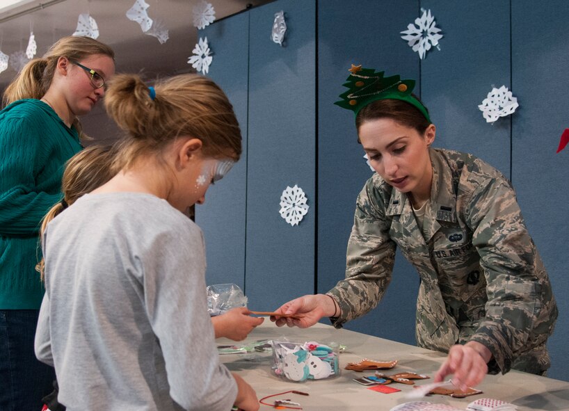 First Lt. Lindsey Byrd, 321st Missile Squadron missile combat crew commander and Operation Provide Joy Board chairman, hands out holiday decorations to children visiting for the 2015 OPJ event Dec. 12 in the Fall Hall Community Center on F.E. Warren Air Force Base, Wyo. Byrd and other 90th Missile Wing volunteers put on the annual event this year. (U.S. Air Force photo by Senior Airman Jason Wiese)