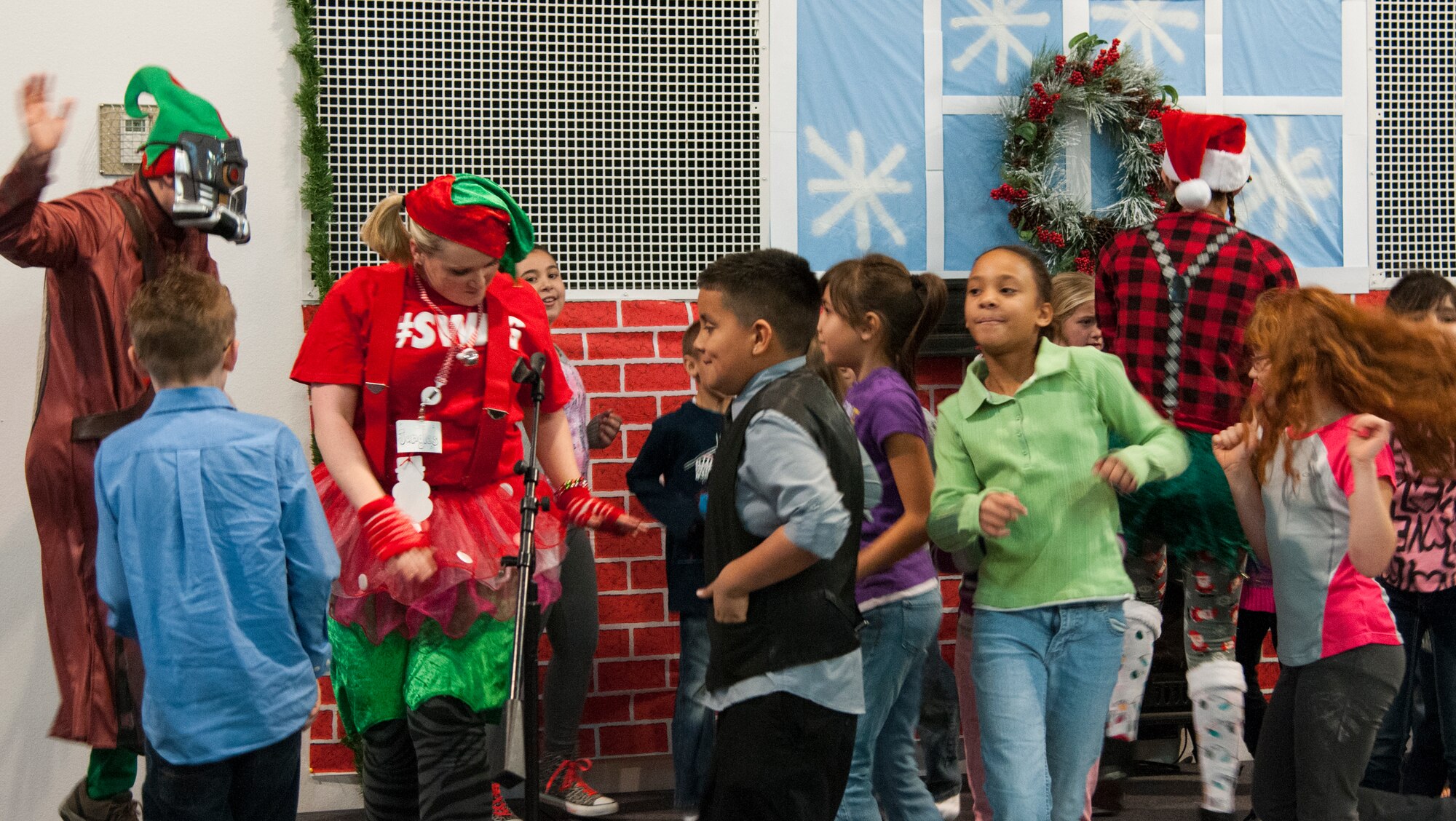 Children dance with Santa Claus' elves during the 2015 Operation Provide Joy event Dec. 12 in the Fall Hall Community Center on F.E. Warren Air Force Base, Wyo. The base and community come together each year to put on the event to bring holiday cheer to local children. (U.S. Air Force photo by Senior Airman Jason Wiese)