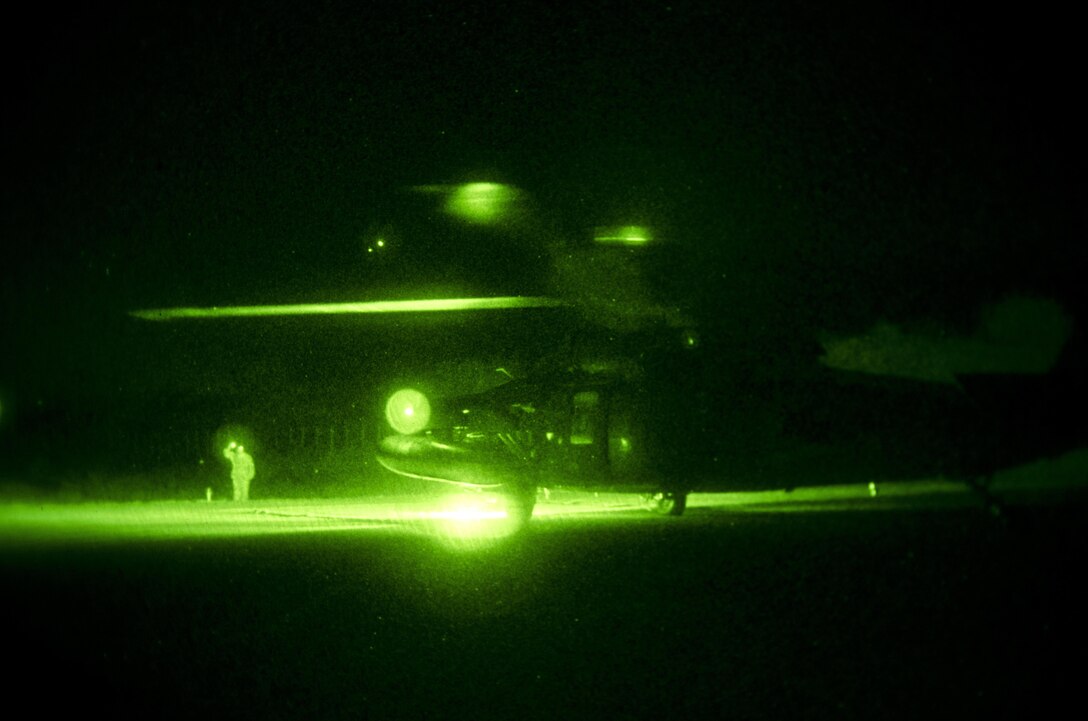 As seen through a night-vision device, U.S. Army Sgt. Rogelio Guzman ground guides a UH- 60 Black Hawk helicopter on Mihail Kogălniceanu Air Force Base, Romania, Dec. 9, 2015. Guzman is a crew chief assigned to the 1st Cavalry Division's 3rd Battalion, 227th Assault Helicopter Battalion, Air Cavalry Brigade. U.S. Army photo by Staff Sgt. Steven M. Colvin