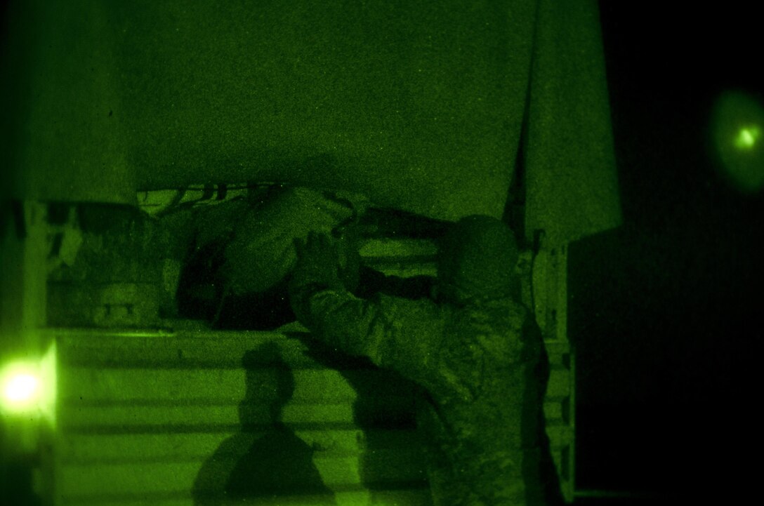 As seen through a night-vision device, a soldier loads gear into a light medium tactical vehicle after arriving on Mihail Kogălniceanu Air Force Base, Romania, Dec. 9, 2015. U.S. Army photo by Staff Sgt. Steven M. Colvin