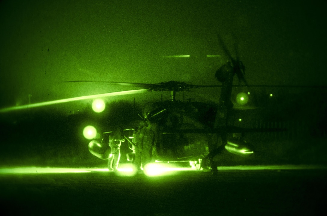 As seen through a night-vision device, soldiers dismount a UH-60 Black Hawk helicopter after arriving on Mihail Kogălniceanu Air Force Base, Romania, Dec. 9, 2015. U.S. Army photo by Staff Sgt. Steven M. Colvin