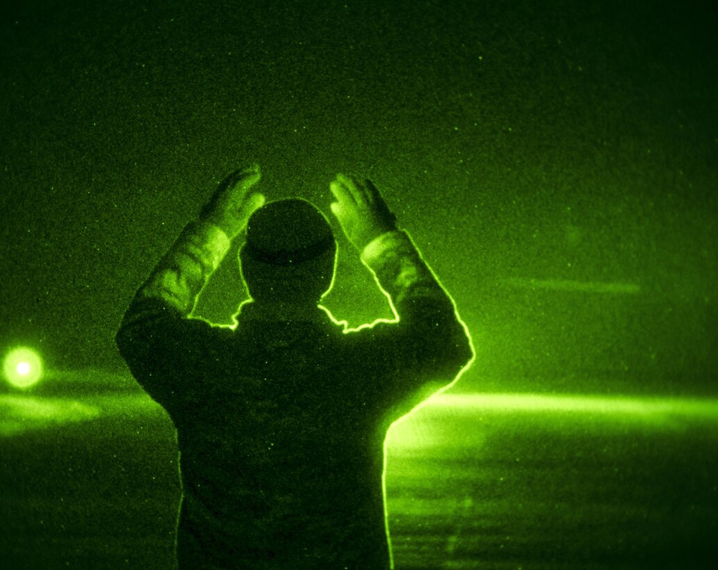 As seen through a night-vision device, U.S. Army Chief Warrant Officer 2 Lucas Gomez ground guides a UH-60 Black Hawk helicopter on Mihail Kogălniceanu Air Force Base, Romania, Dec. 9, 2015. Gomez is a pilot assigned to the 1st Cavalry Division's 3rd Battalion, 227th Assault Helicopter Battalion, Air Cavalry Brigade. U.S. Army photo by Staff Sgt. Steven M. Colvin