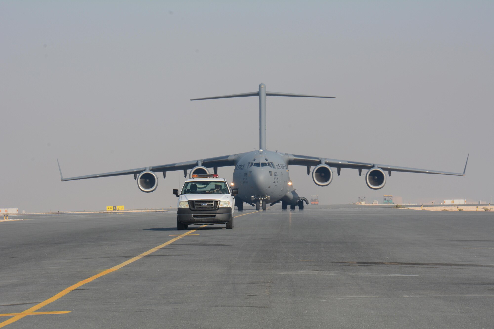 A C-17 Globemaster III is escorted to its parking location at Al Udeid Air Base, Qatar Dec. 13. The aircraft delivered two Apache helicopters from Fort Bliss, Texas. The helicopters are scheduled to take part in the annual Qatar National Day Parade set for Dec. 18. (U.S. Air Force photo by Tech. Sgt. James Hodgman/Released)