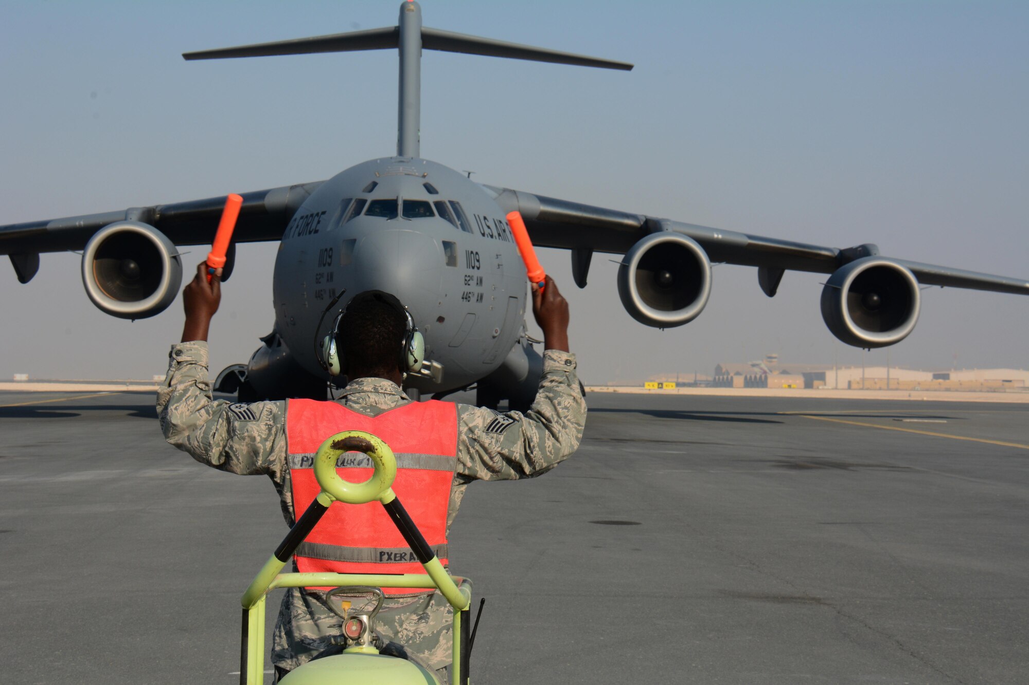 Staff Sgt. Berry Lynch, 8th Expeditionary Air Mobility Squadron avionics specialist, directs a C-17 Globemaster III to its parking location at Al Udeid Air Base, Qatar Dec. 13. The aircraft delivered two Apache helicopters from Fort Bliss, Texas. The helicopters are scheduled to take part in the annual Qatar National Day Parade set for Dec. 18. (U.S. Air Force photo by Tech. Sgt. James Hodgman)
