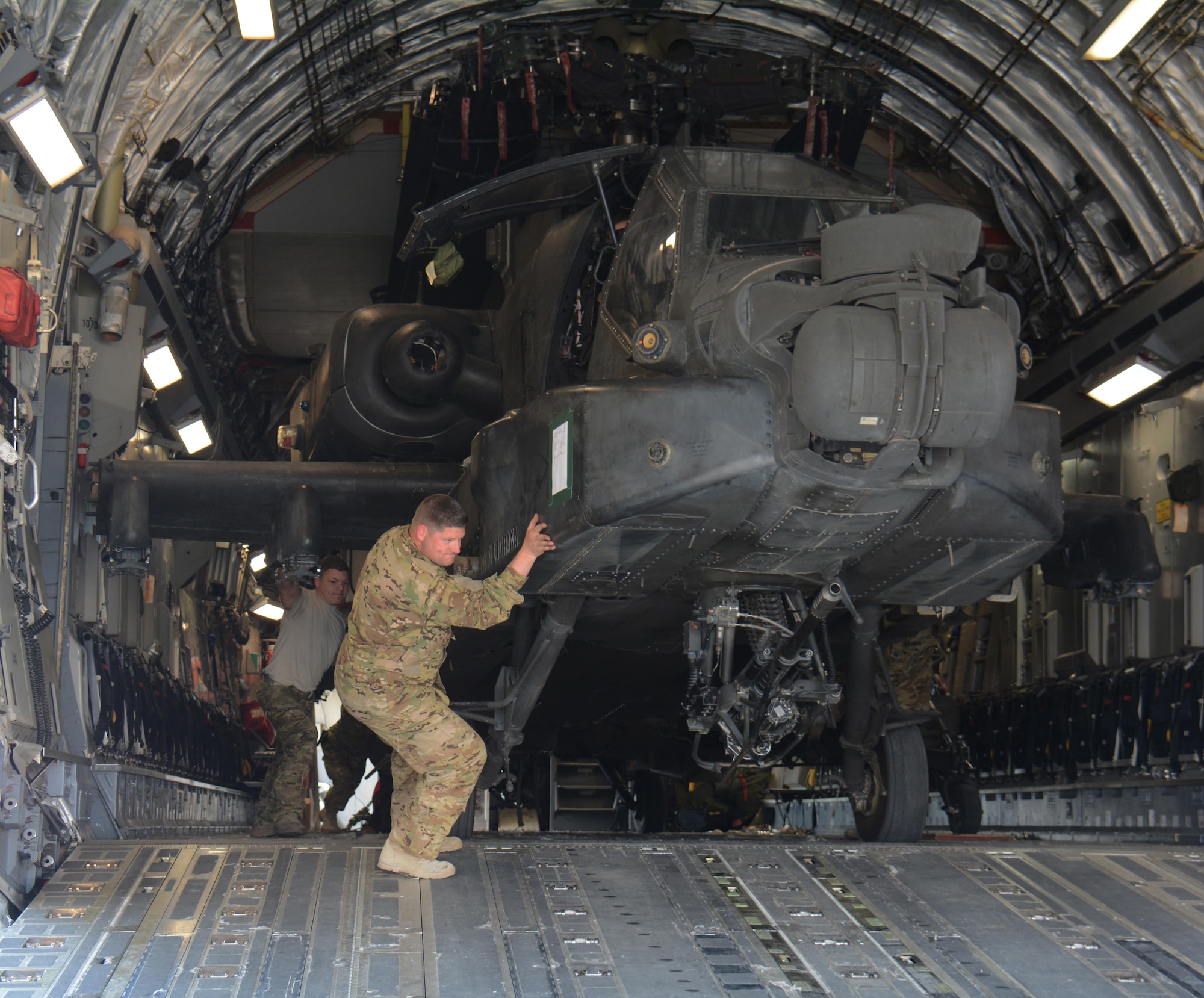 3-6 Heavy Cavalry Regiment soldiers deployed from Fort Bliss, Texas work to move one of two Apache helicopters out of a C-17 Globemaster III at Al Udeid Air Base, Qatar Dec. 13. The C-17, which is deployed from the 62nd Airlift Wing at Joint Base Lewis-McChord, Washington, delivered the helicopters. The helicopters are scheduled to take part in the annual Qatar National Day Parade set for Dec. 18. (U.S. Air Force photo by Tech. Sgt. James Hodgman/Released)