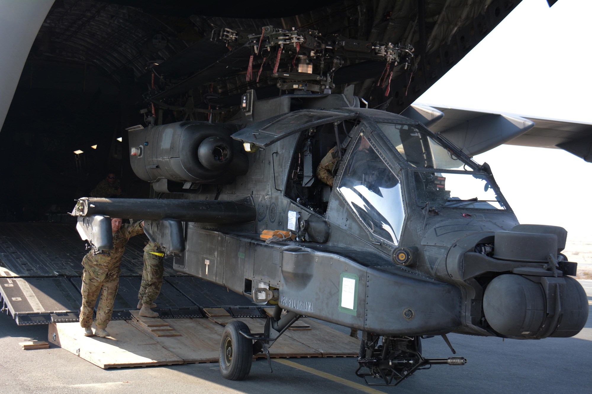 3-6 Heavy Cavalry Regiment soldiers deployed from Fort Bliss, Texas work to move one of two Apache helicopters out of a C-17 Globemaster III at Al Udeid Air Base, Qatar Dec. 13. The C-17, which is deployed from the 62nd Airlift Wing at Joint Base Lewis-McChord, Washington, delivered the helicopters. The helicopters are scheduled to take part in the annual Qatar National Day Parade set for Dec. 18. (U.S. Air Force photo by Tech. Sgt. James Hodgman/Released)