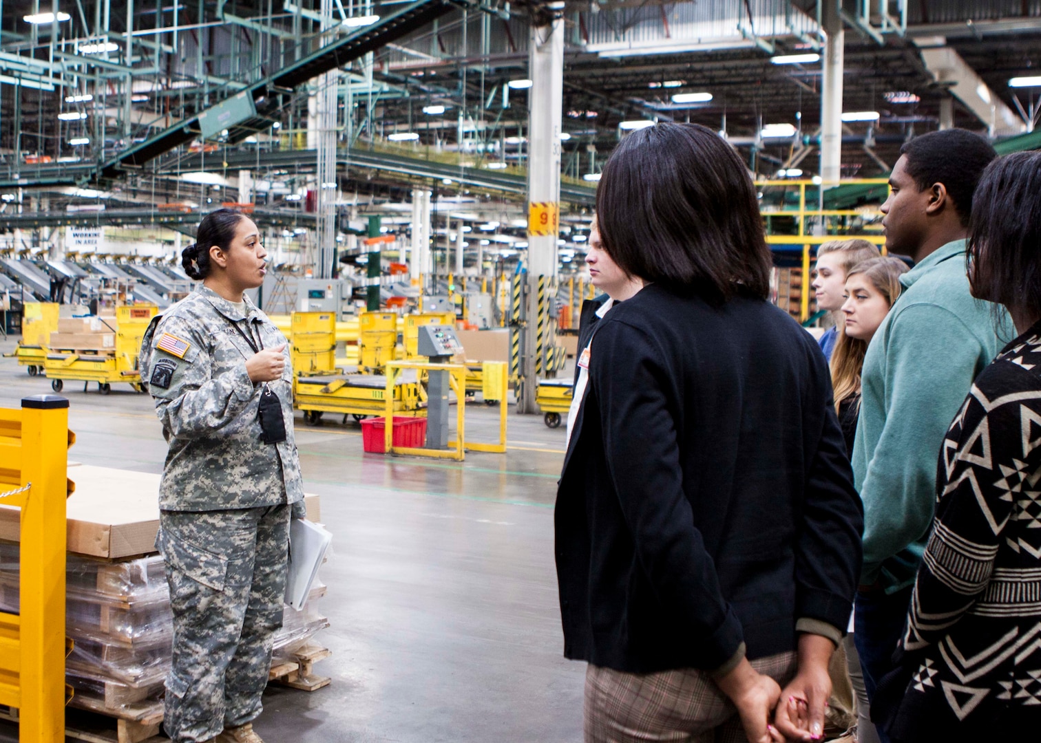 Students from Central York High School talk about real-world logistics inside the Eastern Distribution Center at DLA Distribution Susquehanna, Pa., with Army Chief Warrant Officer 4 Brenda Johnson on Dec. 10. 