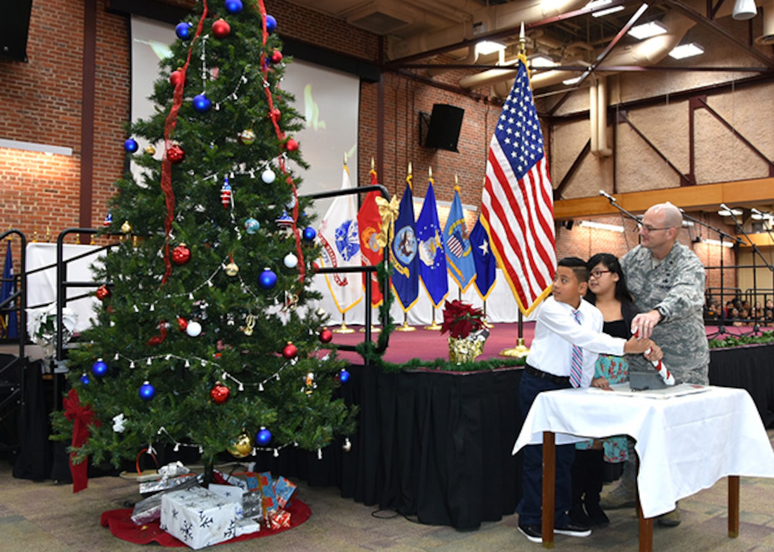 Bensley Elementary School 5th graders, Angela Bernardina Marinex and Andersson Revelo Castro, along with Defense Logistics Agency Aviation Commander Air Force Brig. Gen. Allan Day throw the switch to light the tree during the annual Tree Lighting Ceremony Dec. 10, 2015 in the Frank B. Lotts Conference Center on Defense Supply Center Richmond, Virginia. 