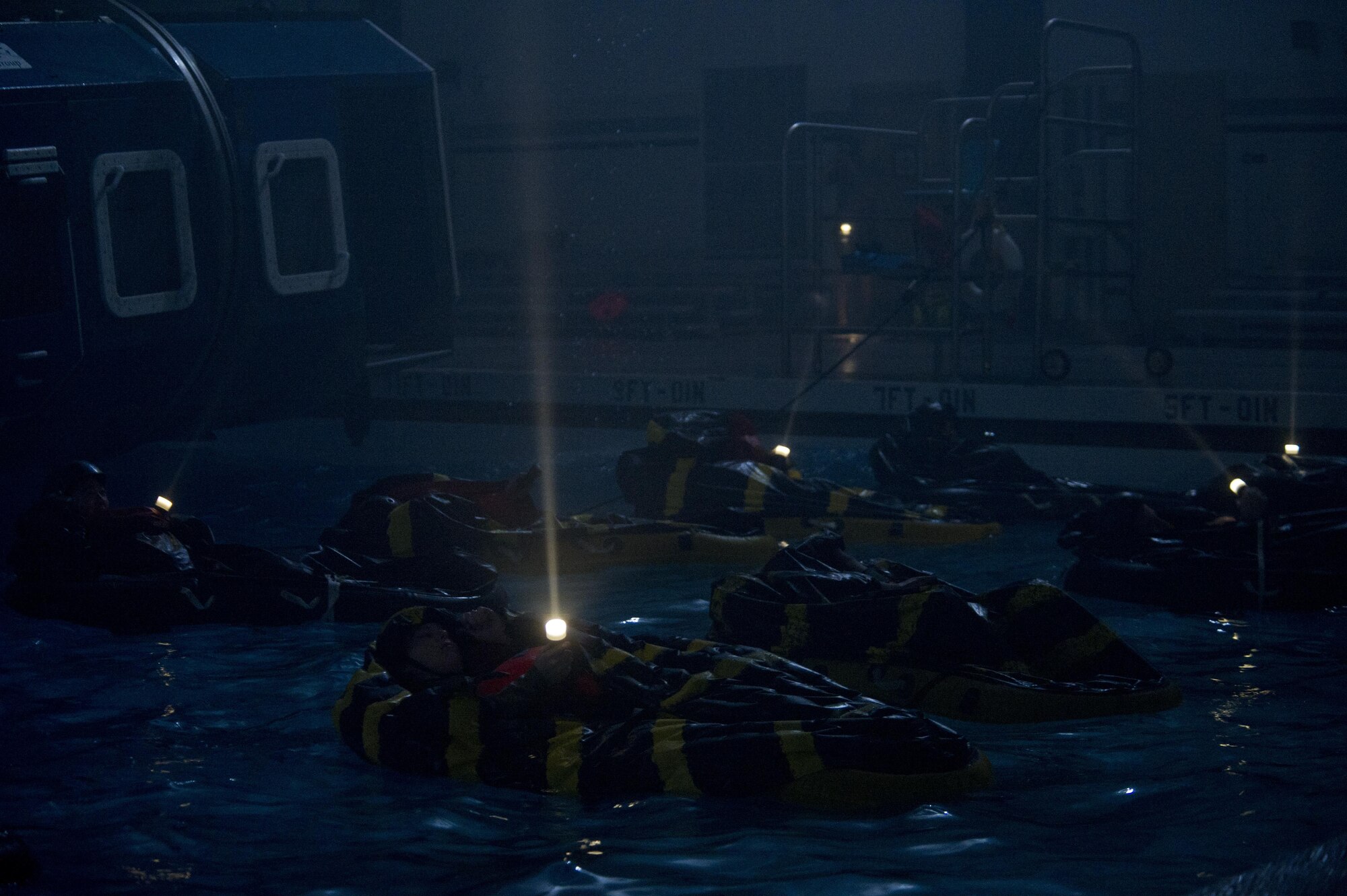 Water survival students wave their flash lights to the simulated rescue forces flying overhead Dec. 8, 2015, at Fairchild Air Force Base, Wash. Students were put through single-man life raft and multi-man life raft scenarios. (U.S. Air Force photo/Airman 1st Class Nick J. Daniello)