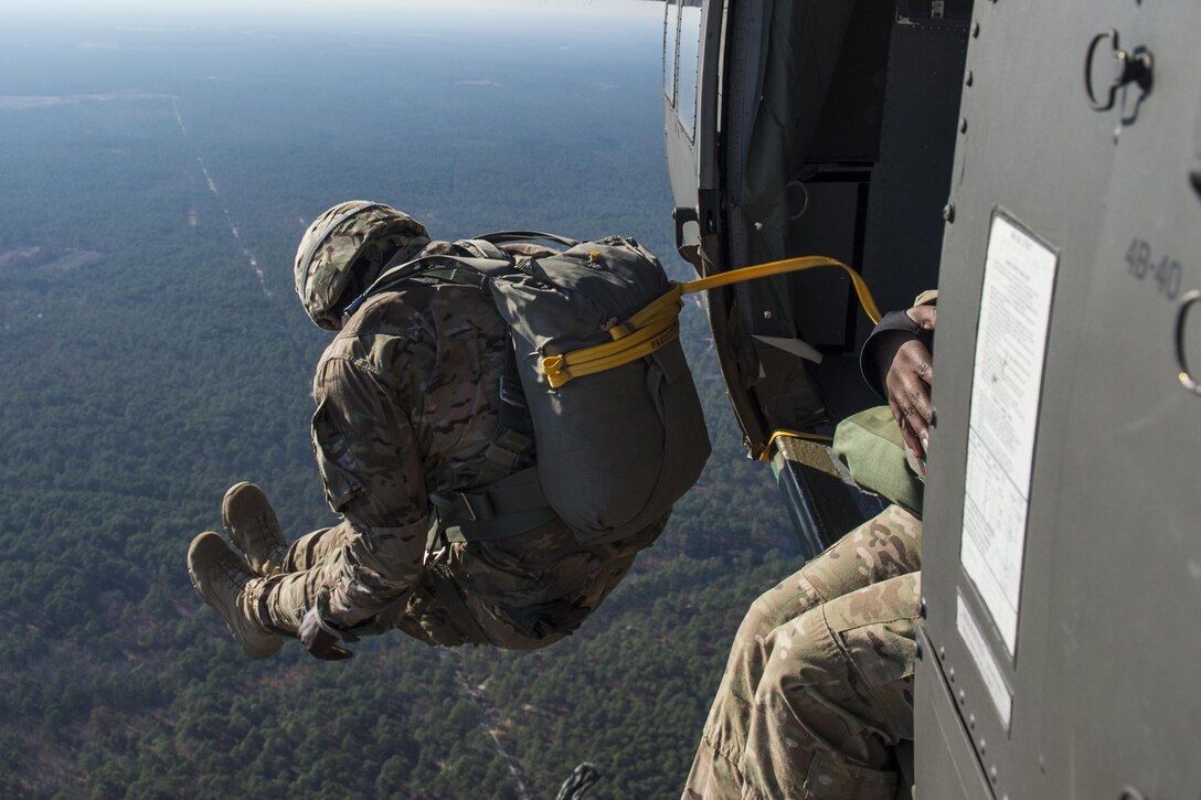 A U.S. soldier jumps out of a UH-60 Black Hawk during the 18th Annual Randy Oler Memorial Operation Toy Drop on Camp Mackall, N.C., Dec. 8, 2015. Operation Toy Drop provides paratroopers from the U.S. and seven partner nations an opportunity to help children receive toys for the holidays. U.S. Air Force photo by Staff Sgt. Douglas Ellis