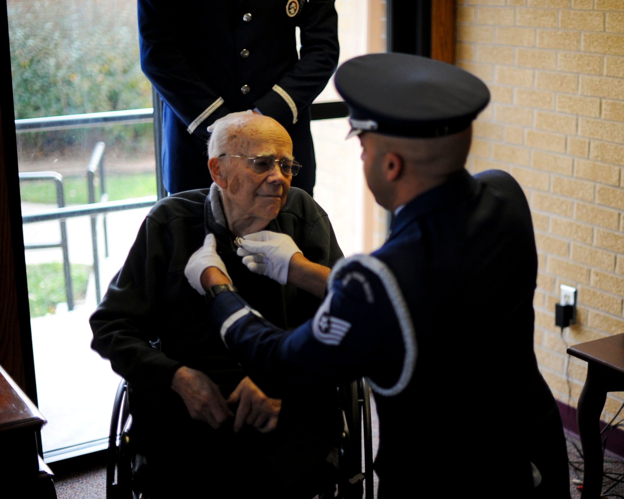 Tech. Sgt. Terrance Williams, the 22nd Air Refueling Wing Honor Guard NCO in charge, places a veteran’s pin on the collar of Roy Mullinax, a World War II veteran, Dec. 8, 2015, in Newton, Kan. Mullinax enlisted in the Army toward the end of WWII before joining the Air Force and working for the federal government for more than 50 years before his retirement in 2004. (U.S. Air Force photo/Senior Airman Victor J. Caputo)