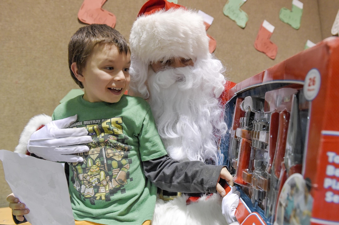 Xavier Hall, 4, receives a new toy from Santa Claus, played by U.S. Marine Corps Sgt. Mauricio Sandoval, during a Toys for Tots event in Nikolai, Alaska, Dec. 11, 2015. The U.S. Marine Corps Reserve runs the program to use toys to deliver a message of hope to less fortunate children. This year three teams of Marines traveled in sub-zero temperatures via snow machine to remote villages near Kotzebue, Galena and McGrath to deliver toys to children. U.S. Air Force photo by Alejandro Pena