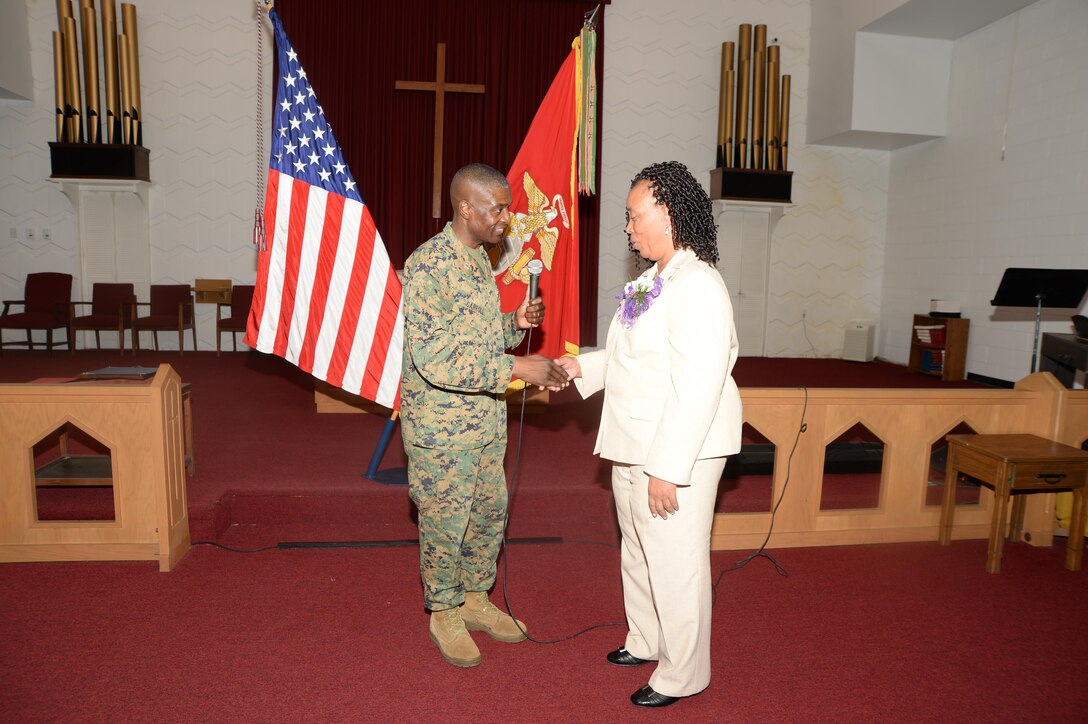 Col. James C. Carroll III, commanding officer, Marine Corps Logistics Base Albany, presents Virginia Williams, IT supervisor, MCLB Albany, with a command coin during her retirement ceremony, Dec. 10, in the base’s Chapel of the Good Shepherd.