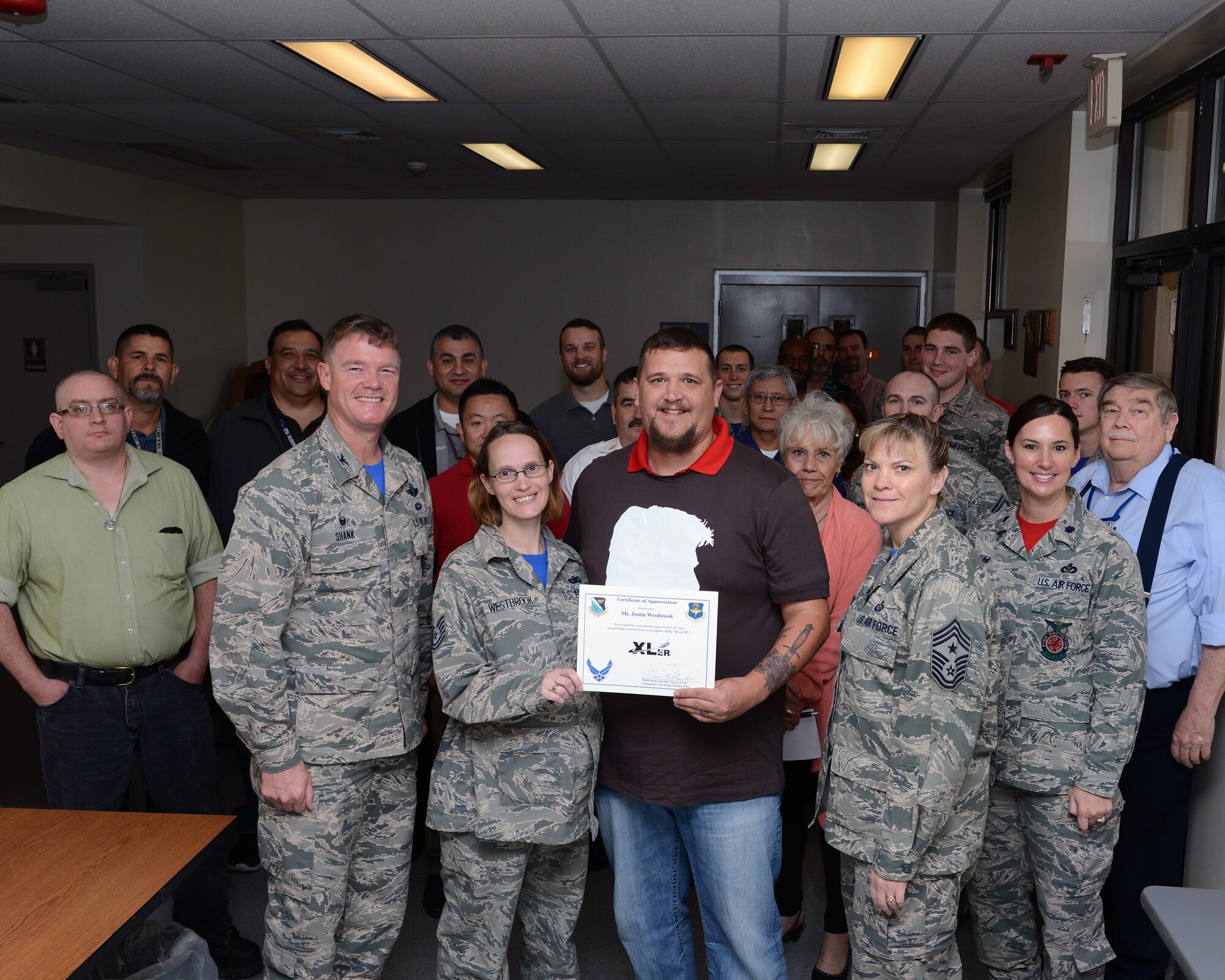 Justin Westbrook, center-right, 47th Civil Engineer Squadron Information Technology specialist, and his wife, Tech. Sgt. Westbrook, center-left, 47th Flying Training Wing commander support staff, pose with Col. Thomas Shank, left, 47th FTW commander, and Chief Master Sgt. Teresa Clapper, 47th FTW command chief, after accepting the “XLer of the Week” award, here, Dec. 11, 2015. The XLer is a weekly award chosen by wing leadership and is presented to those who consistently make outstanding contributions to their unit and Laughlin. (U.S. Air Force photo by Senior Airman Jimmie D. Pike)