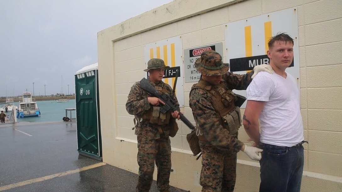 Marines with the 3rd Law Enforcement Battalion search a Marine posing as a terrorist during training at Kadena Marina, Okinawa, Dec. 10, 2015. Marines with military police and Criminal Investigation Division, 3rd LE, III Marine Headquarters Group, III Marine Expeditionary Force, participated in an elaborate week-long exercise to sharpen their tactical investigation skills and practice successfully merging two individual units. The goal of the exercise was to collect evidence at each crime scene to guide them to the next, ultimately resulting in the capture of a simulated terrorist.