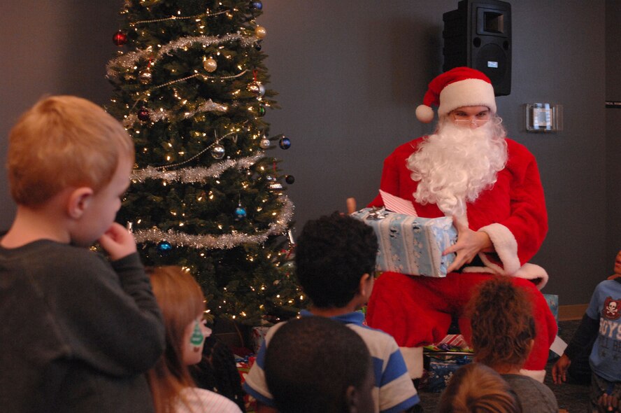 Santa Claus prepares to hand out a present at a party sponsored by the Reconnaissance Crews Booster Club at the Pointe at Rising View, Offutt Air Force Base, Neb., Dec. 12, 2015. The event combined a holiday party with a shopping trip in which underprivileged children received money to spend on winter clothing and shoes. (U.S. Air Force photo/Senior Airman Rachel Hammes)