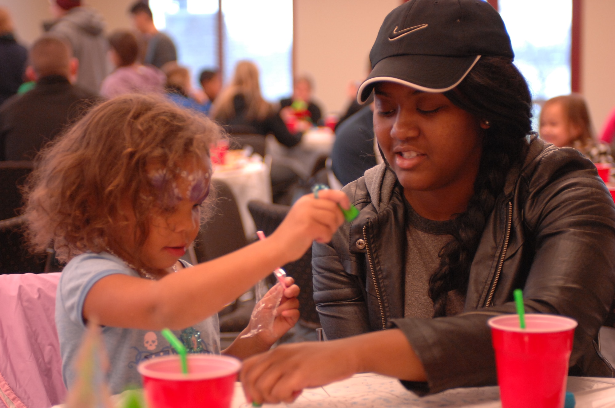 A child attending a holiday party sponsored by the Reconnaissance Crews Booster Club plays a game of tic, tac, toe with her volunteer chaperon at the Pointe at Rising View, Offutt Air Force Base, Neb., Dec. 12, 2015. The event combined a holiday party with a shopping trip in which underprivileged children received money to spend on winter clothing and shoes. (U.S. Air Force photo/Senior Airman Rachel Hammes)