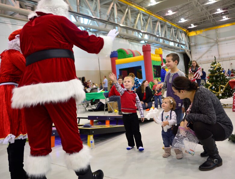 Children wave to Santa and Mrs. Claus at the third annual Children's Holiday Party Dec. 12, 2015, at Creech Air Force Base, Nevada. The event included many activities to bring Creech families together, improve morale and camaraderie, as well as, provide opportunities for children to meet Santa and win presents. (U.S. Air Force photo by Airman 1st Class Christian Clausen/Released)