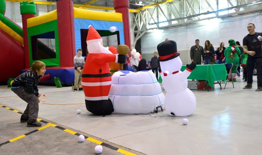 Tyler, 10, son of Master Sgt. Jessica, 432nd Operations Support Squadron intelligence superintendent, takes cover from snowballs thrown from Senior Airman Christopher, 799th Air Base Squadron, fitness center journeyman, in a game called Yeti Attack during the third annual Children's Holiday Party Dec. 12, 2015, at Creech Air Force Base, Nevada. The game involved having children run from one point to another and back while dodging snowballs, if done successfully, they won free Christmas presents. (U.S. Air Force photo by Airman 1st Class Christian Clausen/Released)