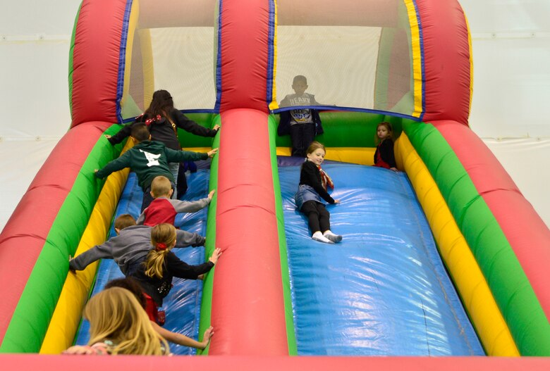 Children enjoy a bouncy house during the third annual Children's Holiday Party Dec. 12, 2015, at Creech Air Force Base, Nevada. The event included many activities to bring Creech families together, improve morale and camaraderie, as well as, provide opportunities for children to meet Santa and win presents. (U.S. Air Force photo by Airman 1st Class Christian Clausen/Released)