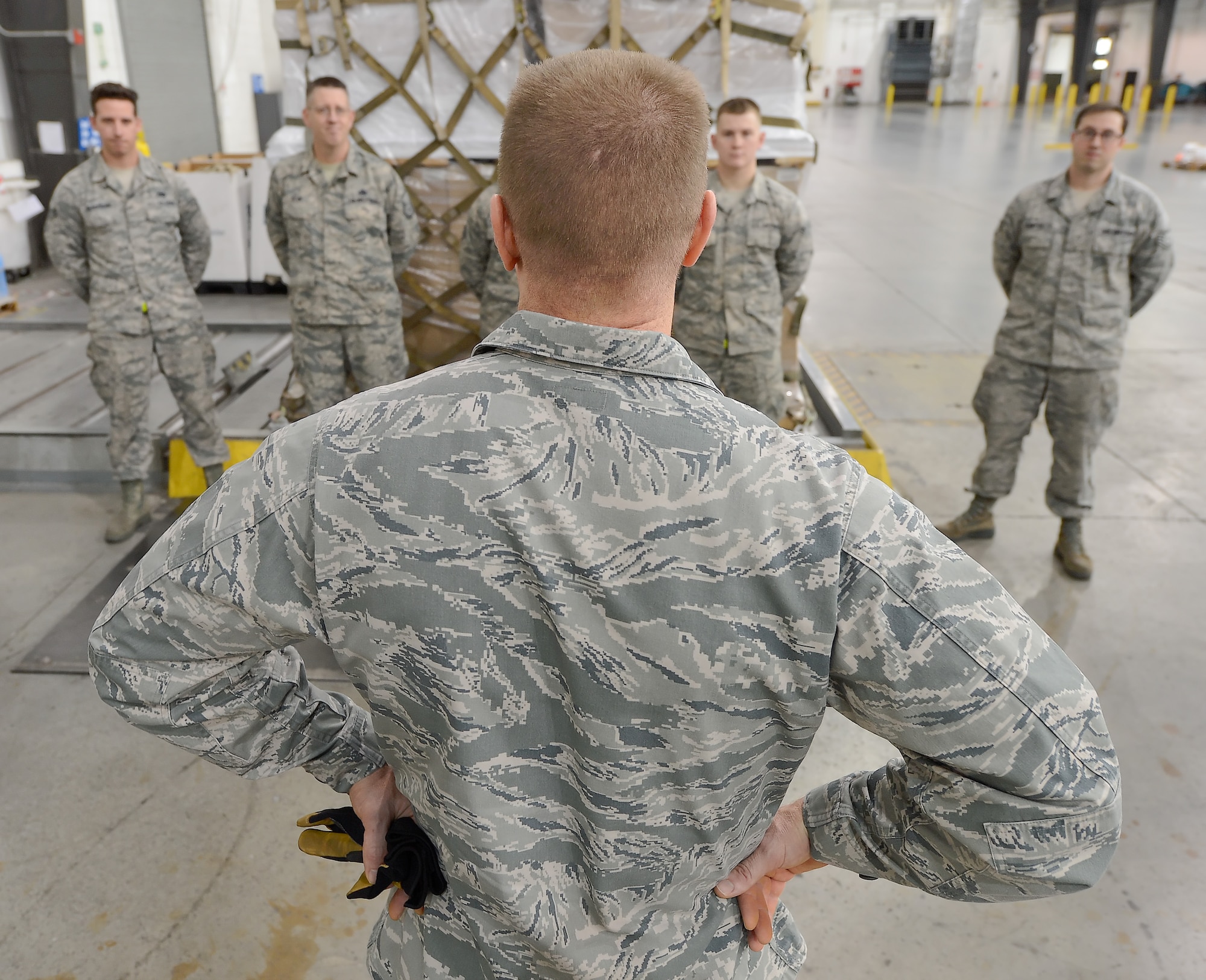 Col. Michael Grismer, 436th Airlift Wing commander, talks with Airmen from the 436th Aerial Port Squadron after joining them to build an air-transportable cargo pallet Dec. 10, 2015, at Dover Air Force Base, Del. Grismer worked with the small team of specialists to build pallets and experience their mission first-hand. (U.S. Air Force photo/Greg L. Davis)