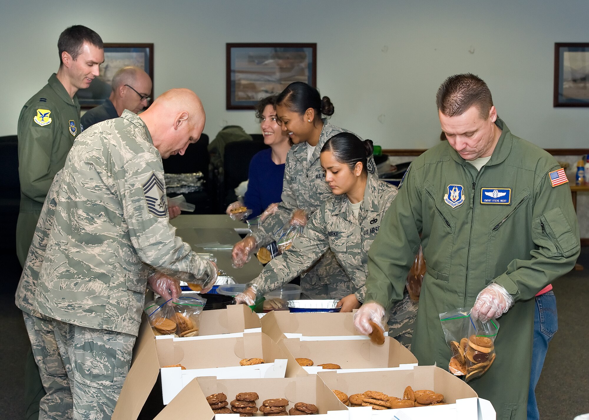 Members of the Dover Chiefs Group, first sergeants, Dover Top 3, Team Dover 5/6 Junior NCO Association, Airman's Council, retirees, spouses and volunteers package baked goods for dormitory residents Dec. 7, 2015, in the 9th Airlift Squadron auditorium on Dover Air Force Base, Del. Baked goods donated by local area businesses and individuals, filled 542 paper bags donated by the USO and decorated by students at local elementary schools and Dover AFB Youth Center patrons for the annual holiday cookie drop. (U.S. Air Force photo/Roland Balik)